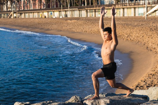 Young man doing yoga pose on seashore