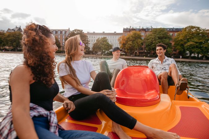 Group of young people sitting on pedal boat in lake