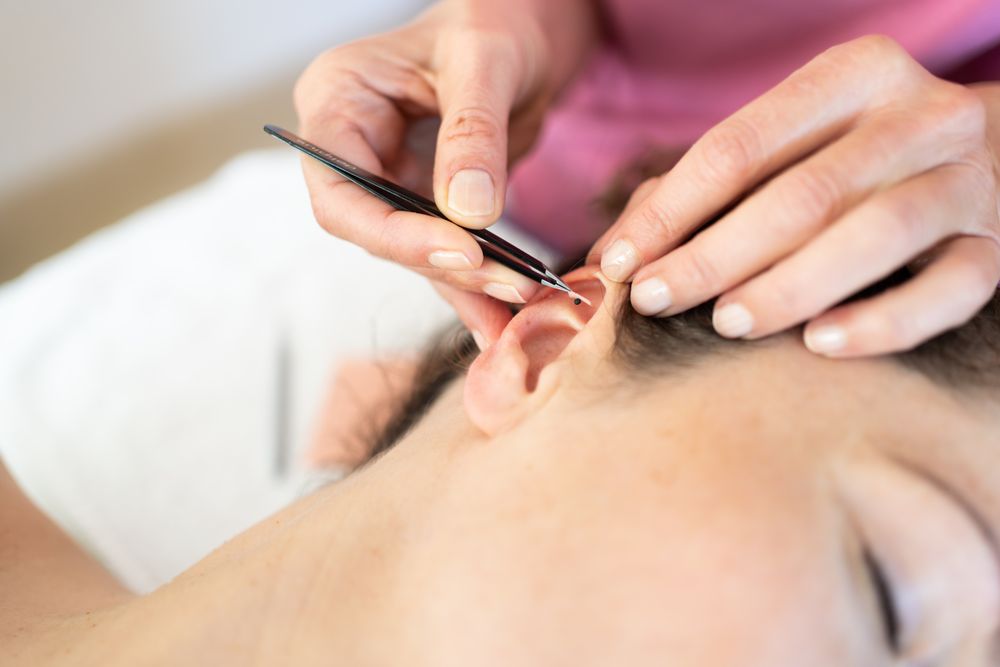 Professional doing ear treatment in clinic