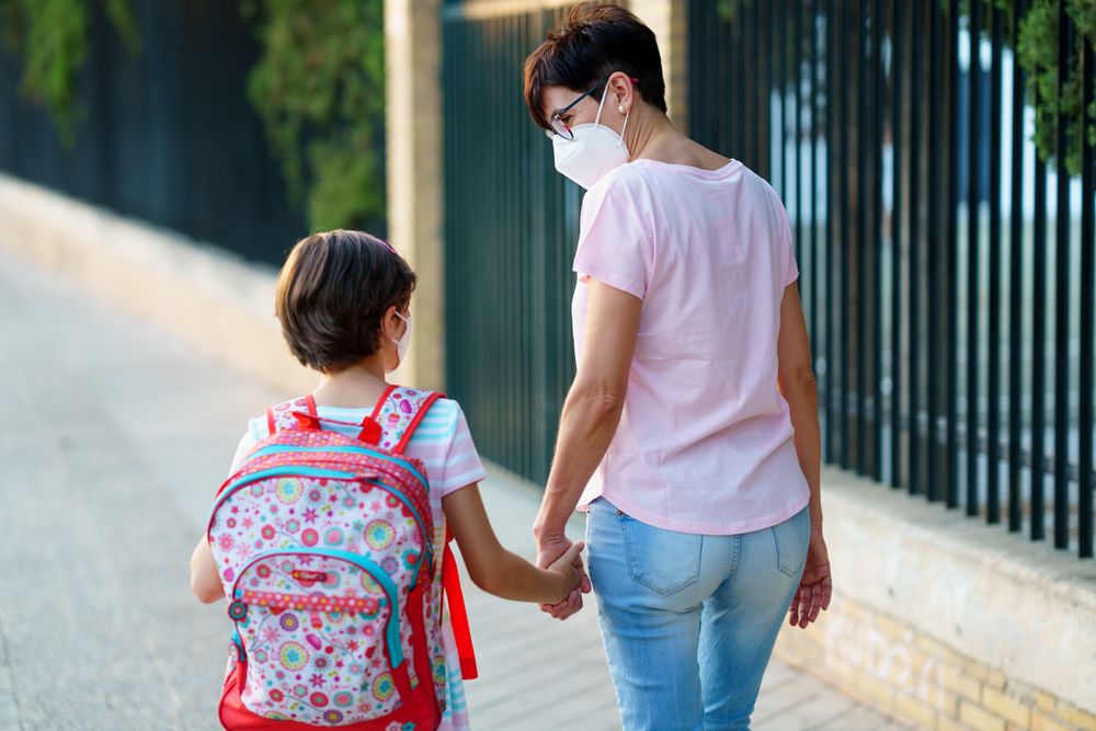 Mother and daughter walking to school in face masks