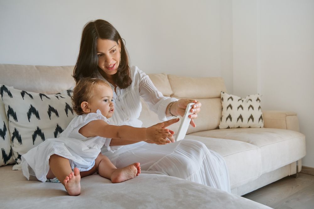 Mother and daughter using smartphone on sofa