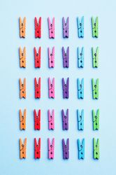 Rainbow colored clothes pins on light blue background
