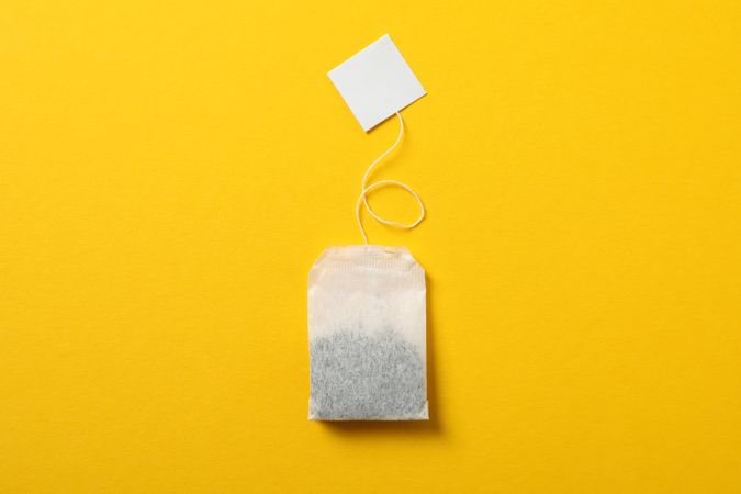 Tea bag with label on yellow background, space for text
