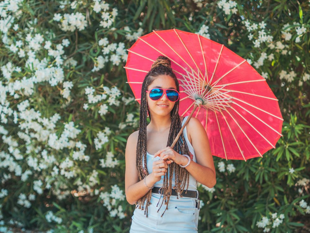 Fit young female with umbrella standing near blooming trees