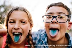 Happy teenage boy and girl having fun outdoors sticking out their tongues after candy 5ry6d0