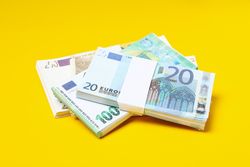 Many bundles of euros on a yellow background.