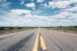 Asphalt road at scenic mountain valley and power line