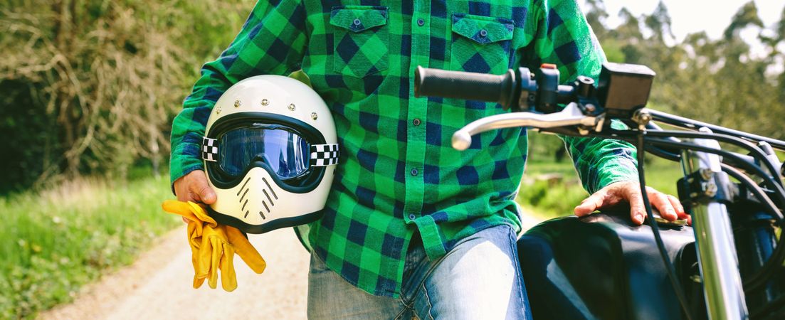 Man posing with motorcycle, helmet and gloves