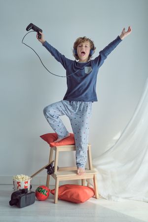 Excited kid rejoicing win in video game with game pad