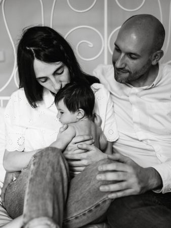 Parents hugging baby on bed