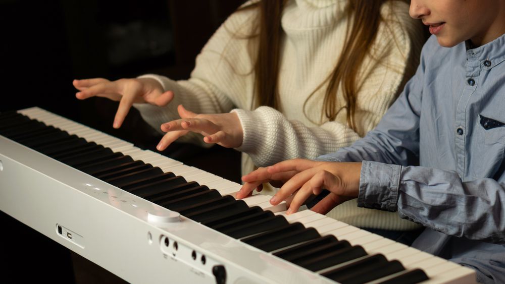 Hands of two children playing the keyboard simultaneously.