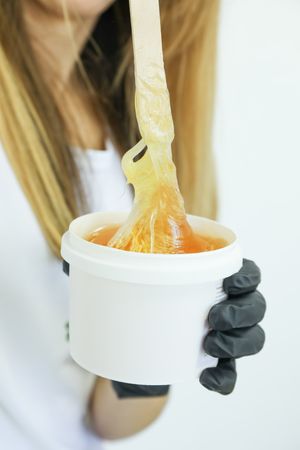 Woman holding liquid yellow paste for sugaring