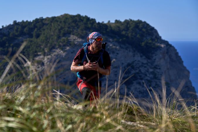 Male hiker with backpack in mountains in sunny day