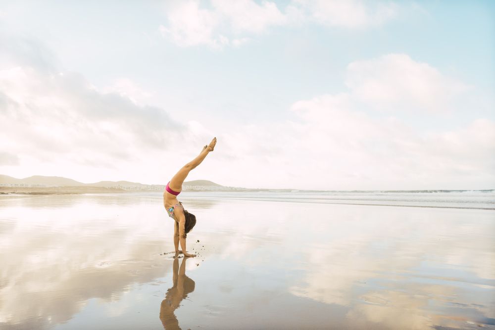 Woman doing handstand near sea