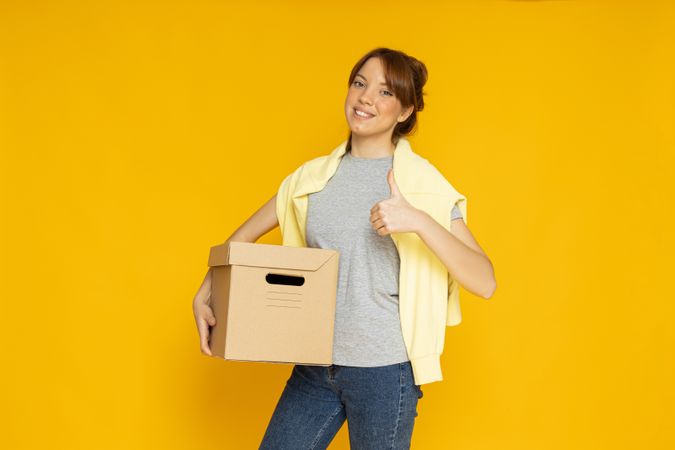 Happy woman with a box on a yellow background