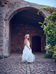 Pretty young girl in wedding dress standing at ancient building