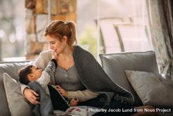 Little boy touching mouth of his mother sitting in living room 0yzQ75