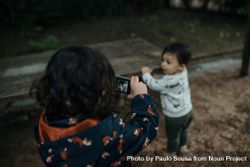 Little girl taking a photo of her brother bDYBV0