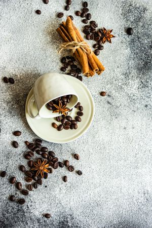 Top view of coffee beans in cup with cinnamon sticks and star anise
