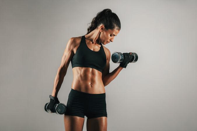 Woman with toned muscular body lifting weights