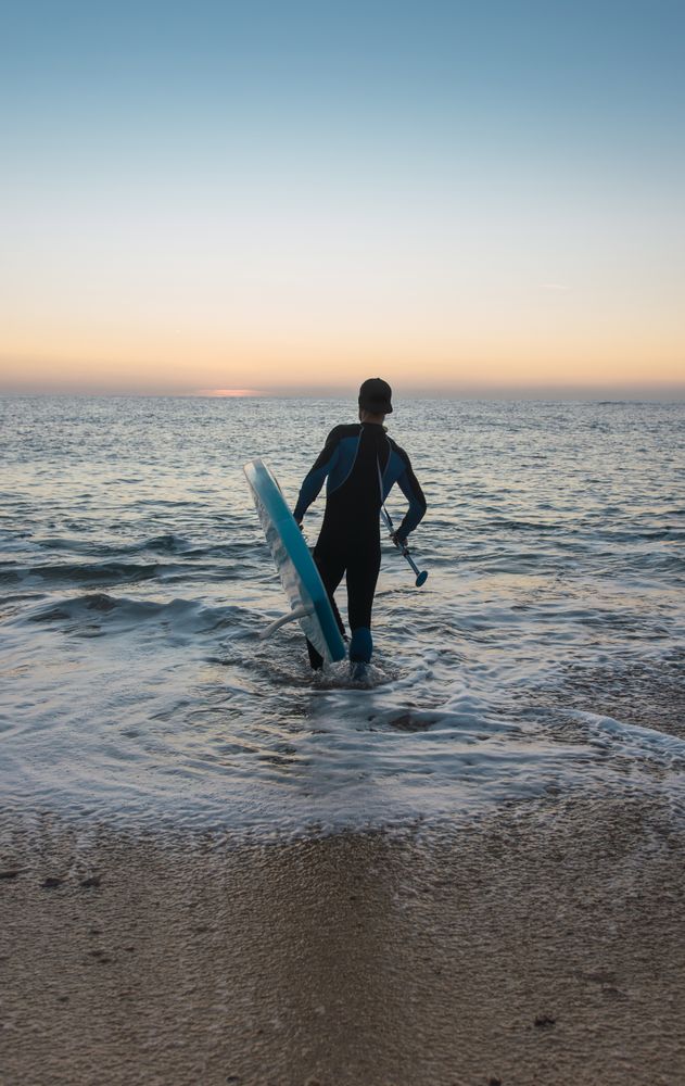 Man practicing paddle surfing with neoprene in a sunrise