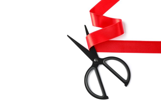 Red ribbon and scissors isolated on blank background. Gift concept