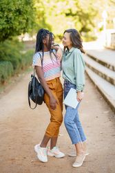 Female friends smiling together in casual clothing in park walk way