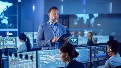 Professionals in a Modern Control Room Analyze Data on Multiple Screens, Ensuring Cybersecurity and Seamless Operations.