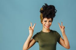 Studio shoot of Black woman smiling making the peace sign with both hands