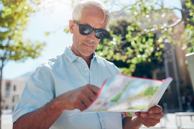 Close up shot of a man reading a map reading a map while standing outdoors