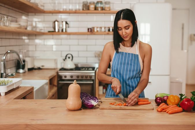 Young woman chopping carrots on cutting board