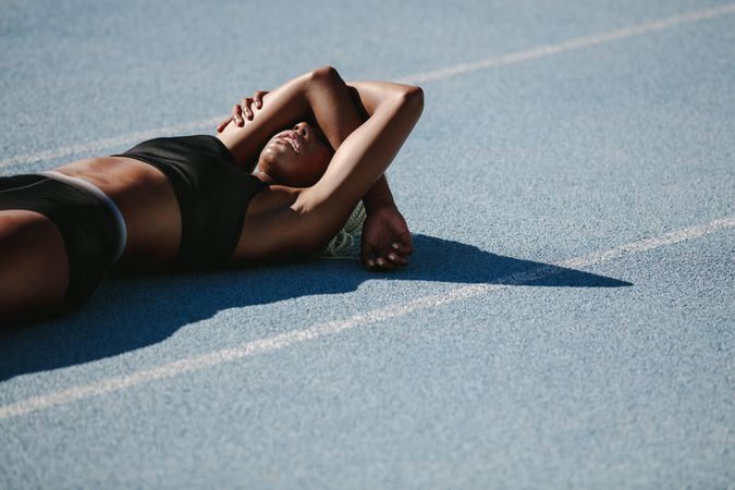 Woman athlete lying on the running track relaxing after workout
