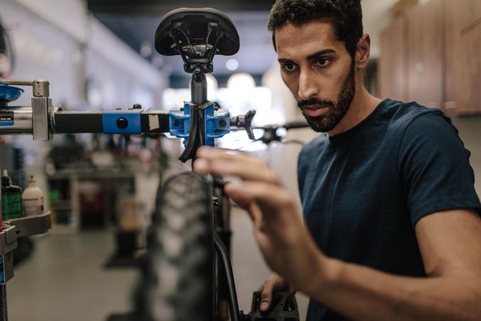 Man with beard concentrating on fixing a bicycle wheel