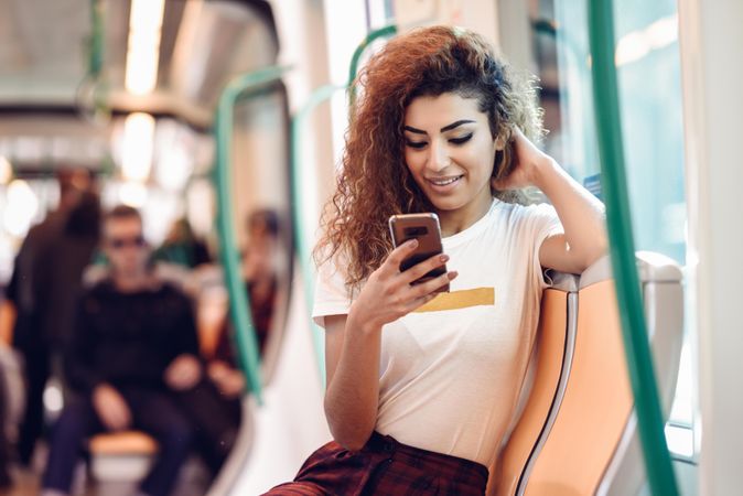 Arab woman sitting in subway carriage checking phone