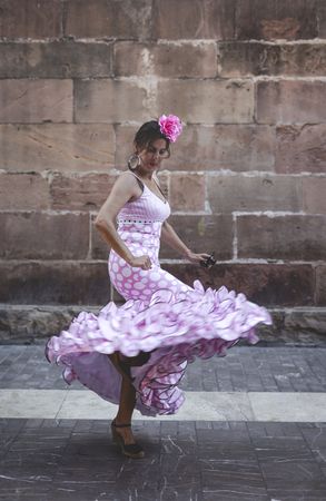 Passionate woman in flamenco dress dancing on street
