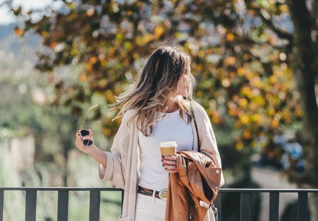 thoughtful woman leaning on handhold and looking along