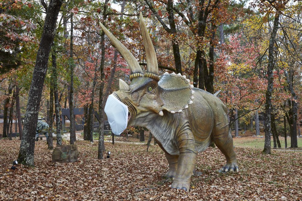 A menacing Triceratops dinosaur figure in a protective mask, AR