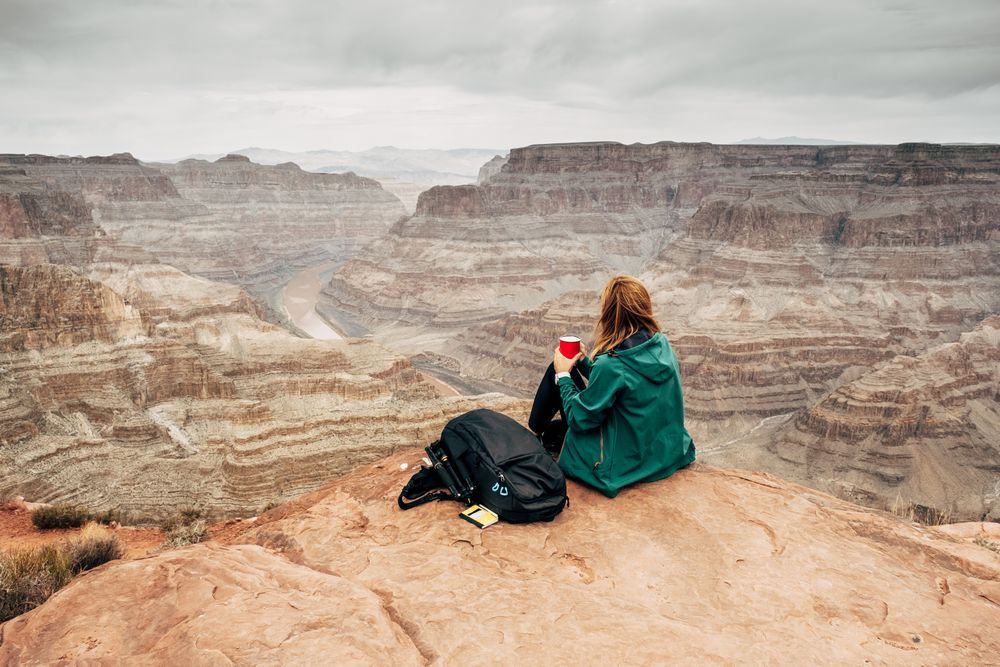 Female relaxing on cliff and admiring picturesque view