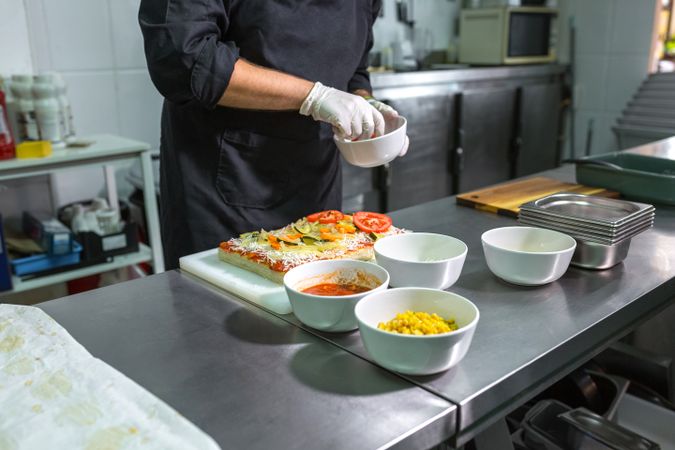 Unrecognizable chef preparing vegetarian focaccia with healthy ingredients in a restaurant kitchen