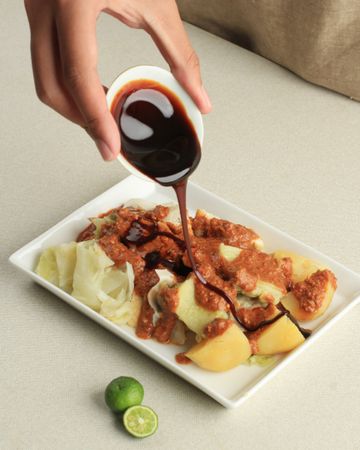 Person pouring condiment over steamed dumplings