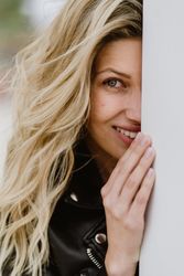Charming tender woman standing behind white wall
