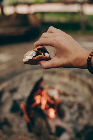 Focus on hand holding s’more dessert at campground