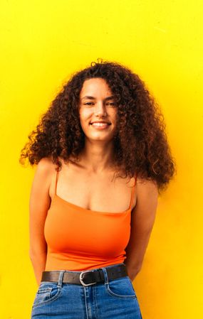 Latina woman portrait leaning on a yellow wall
