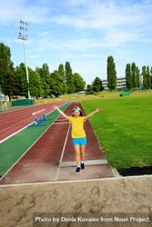 Playful girl performing long jump on track and field 0v7dB5