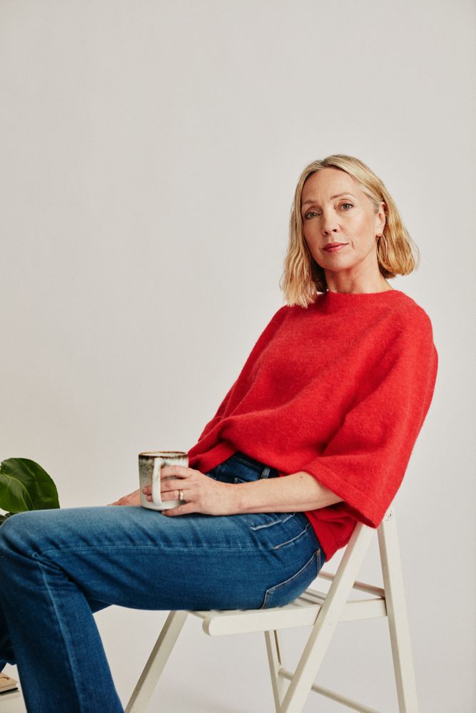 Woman in red sweater sitting on a chair in studio
