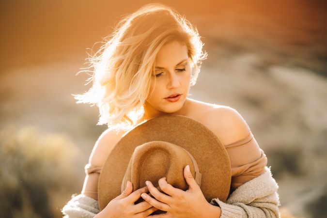 Tender woman holding straw hat on nature