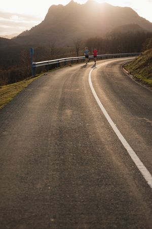 Sportsmen running on asphalt road in mountains