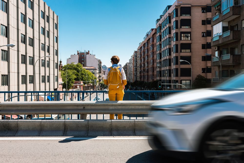Stylish pensive woman contemplating city while standing on road bridge