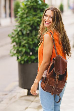 Latina woman looking around outside with leather backpack