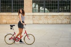 a young woman rides her bicycle across a pedestrian plaza with h
